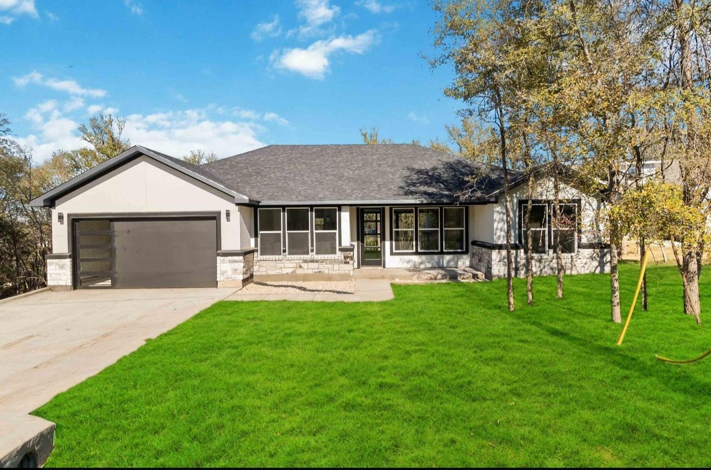 Front elevation of a single-story stucco and stone home with attached two-car garage