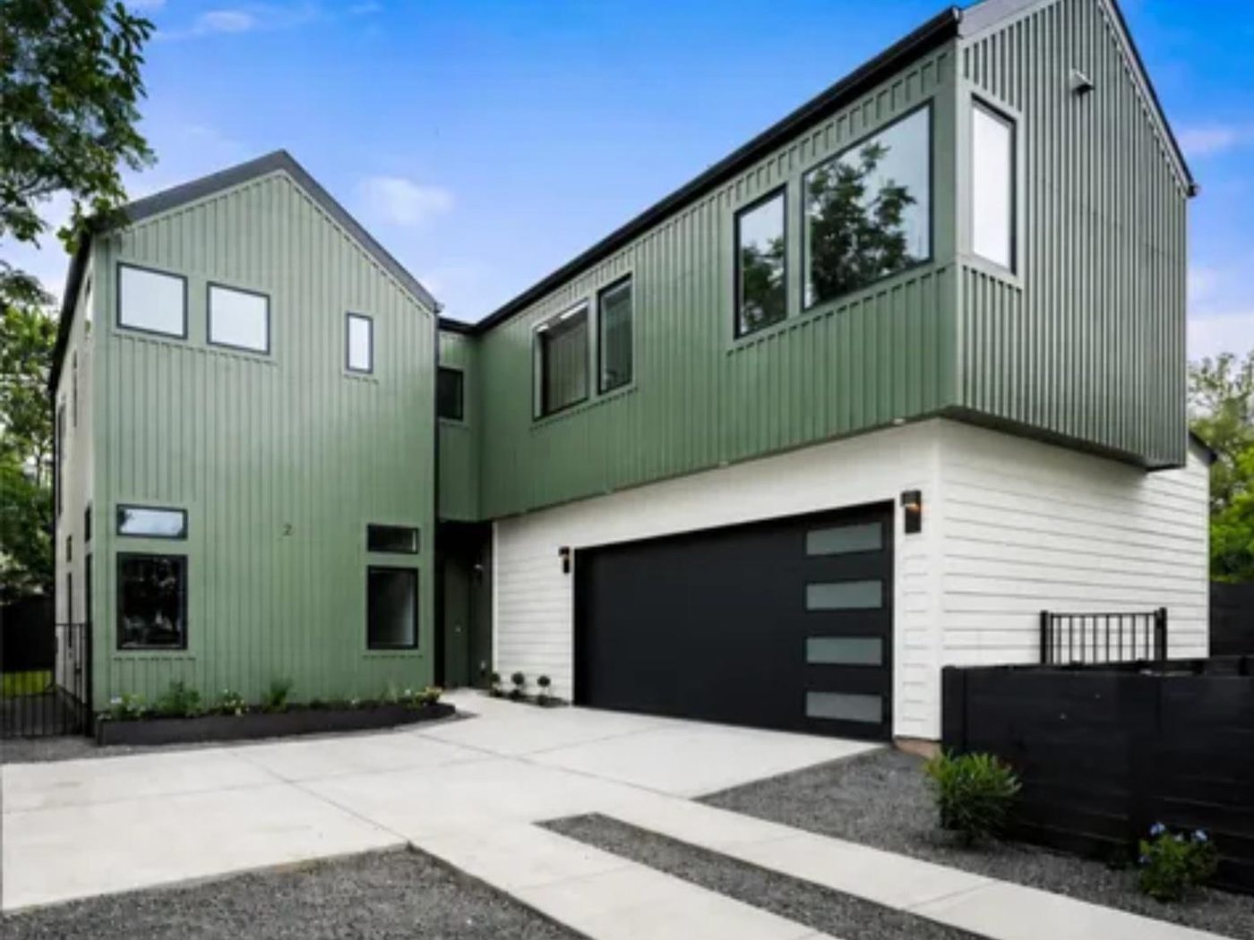 Front elevation of a modern green and white two-story home with attached garage